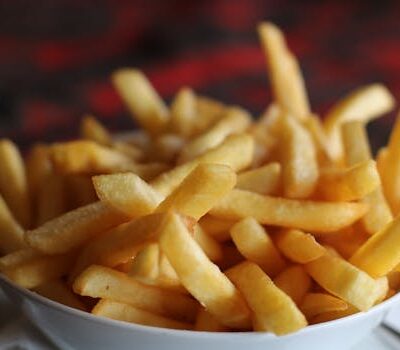 Delicious crispy golden french fries served in a white bowl, perfect for a tasty snack.