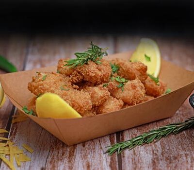 Delicious crispy fried shrimp served with fresh lemon and herbs on a rustic wooden table.